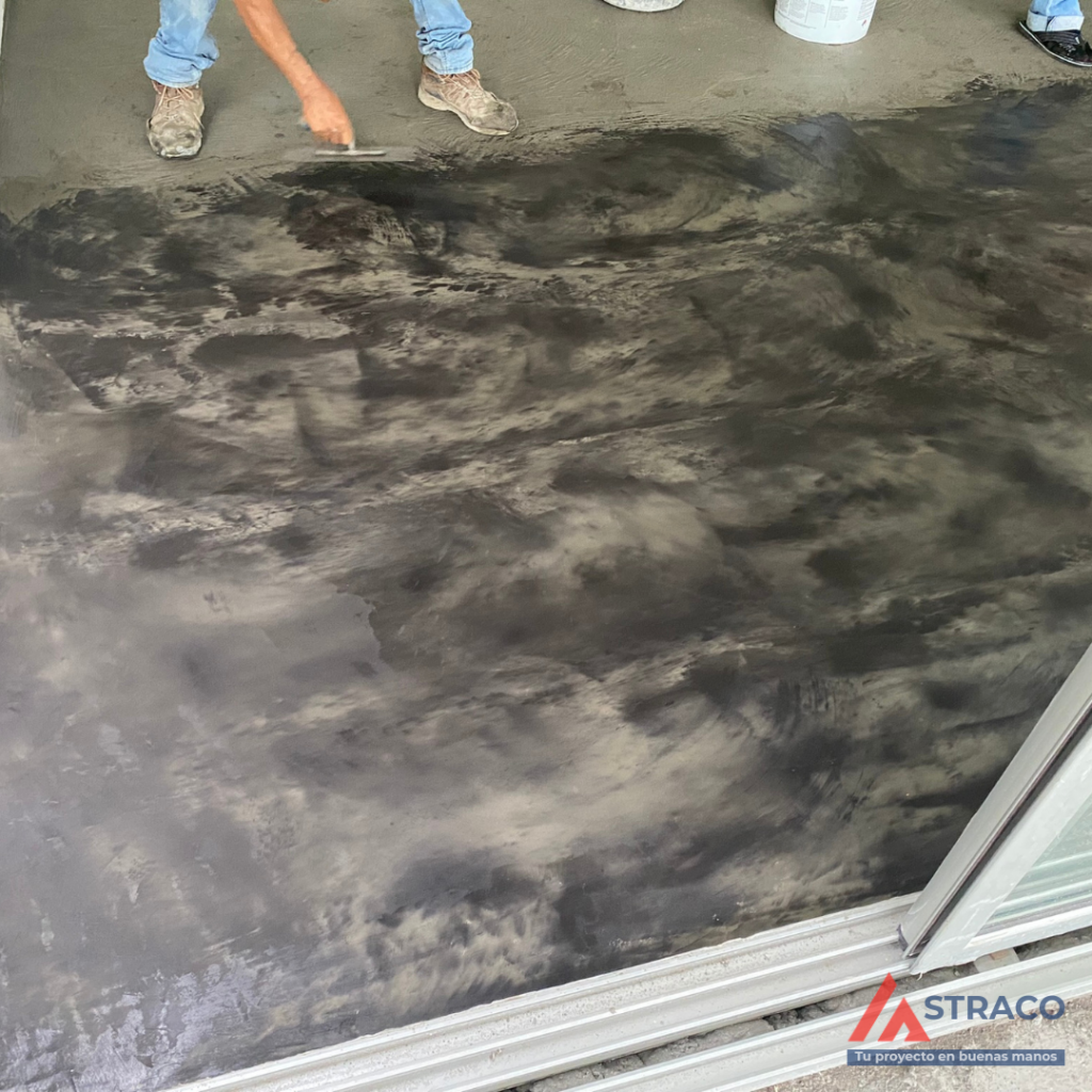 Worker finishing polished concrete floor by hand during construction process in Boquete, Panama